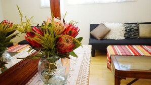 A living room with a sofa, a coffee table, and a vase with flowers. - Moon House (Diamond Creek)