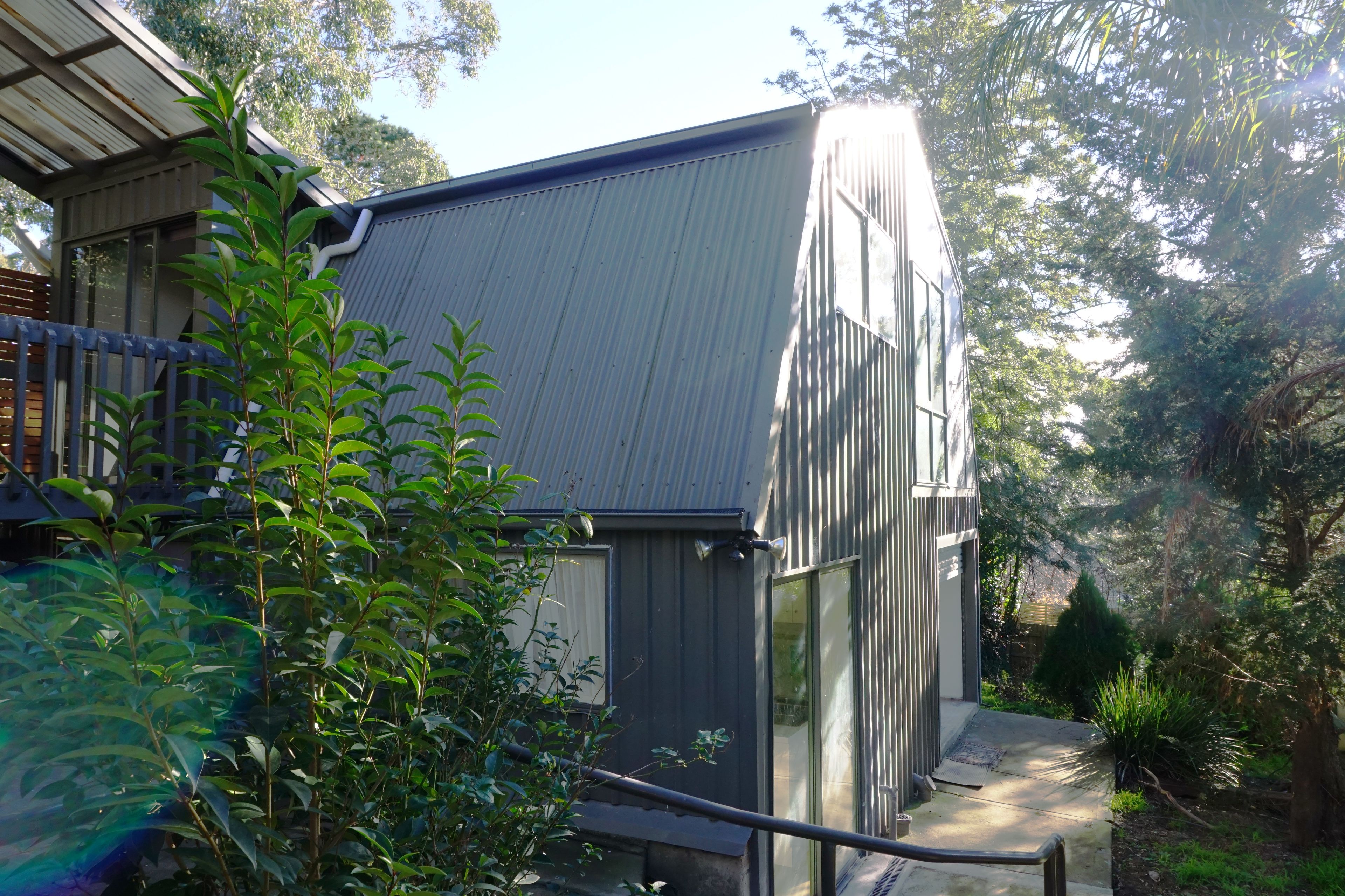 Un bâtiment moderne doté d’un toit en pente, entouré d’une végétation luxuriante et d’arbres.