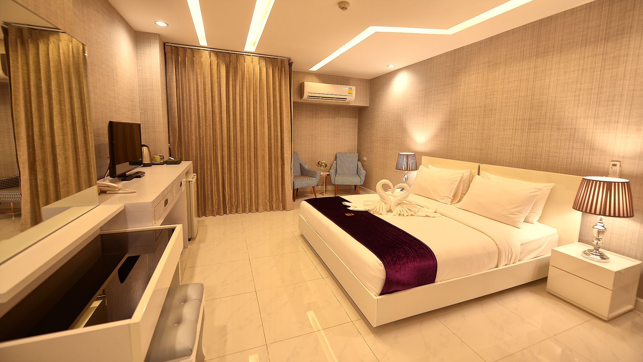 Une chambre d’hôtel moderne équipée d’un grand lit, d’un bureau, d’une chaise, d’une coiffeuse et d’un appareil de climatisation.