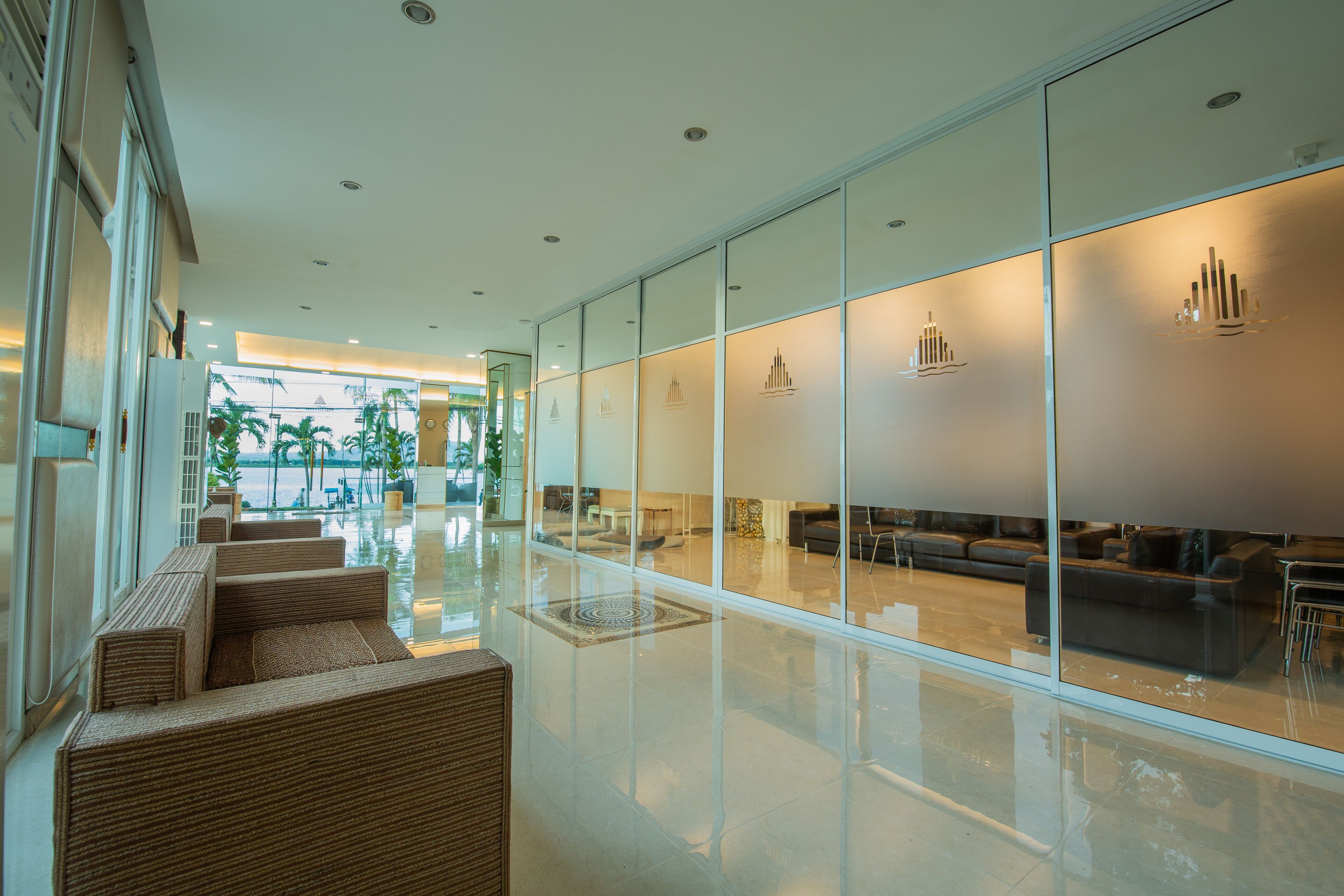 A modern hotel lobby with a glass partition, seating area, and a view of the outdoor pool.
