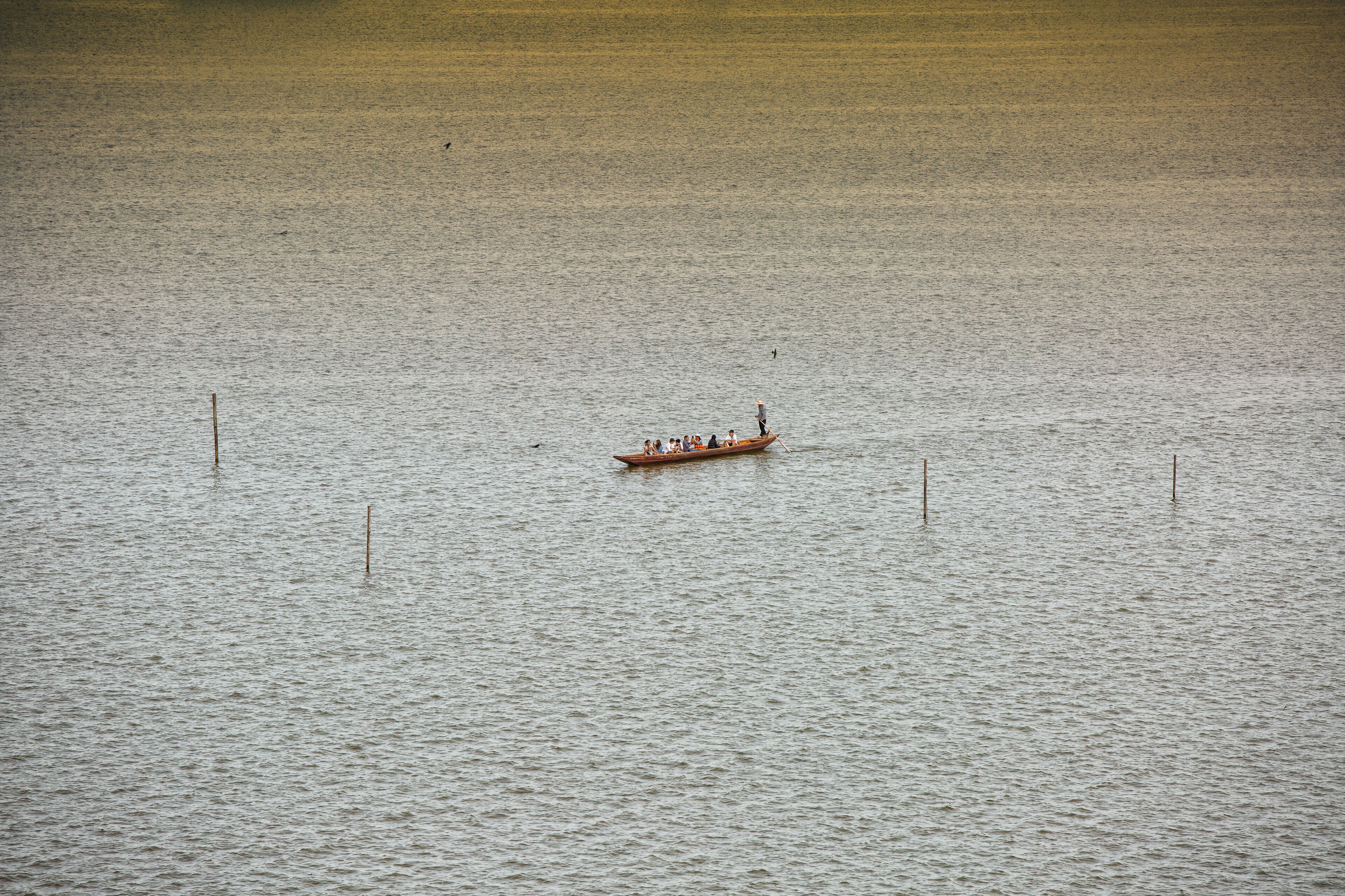 A boat on calm water with a few people on board.