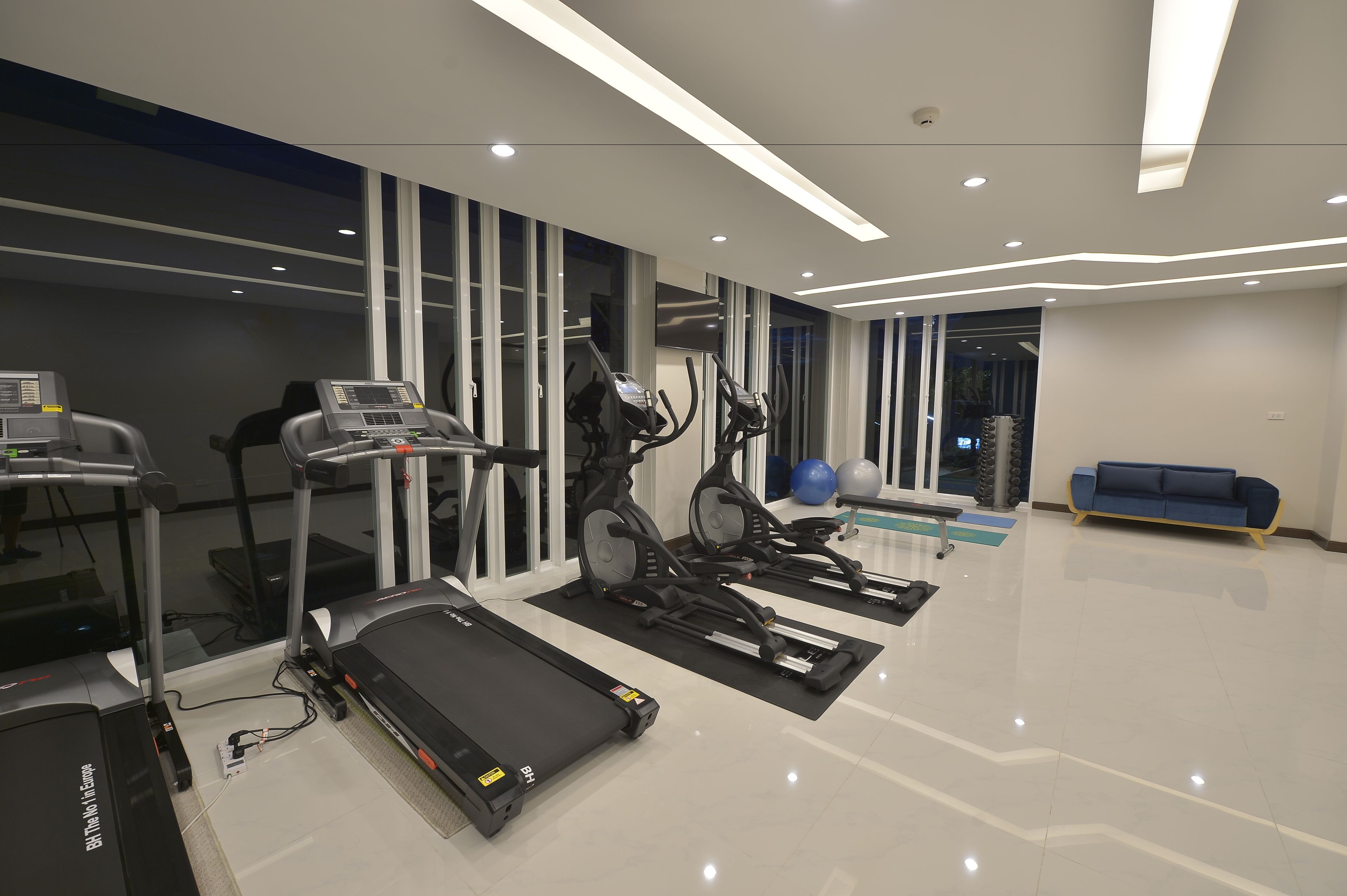 A modern gym with treadmills, elliptical machines, and exercise balls.