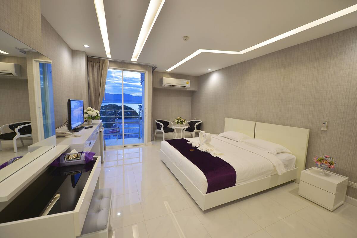 A modern hotel room with a bed, bedside table, and a desk with a computer.