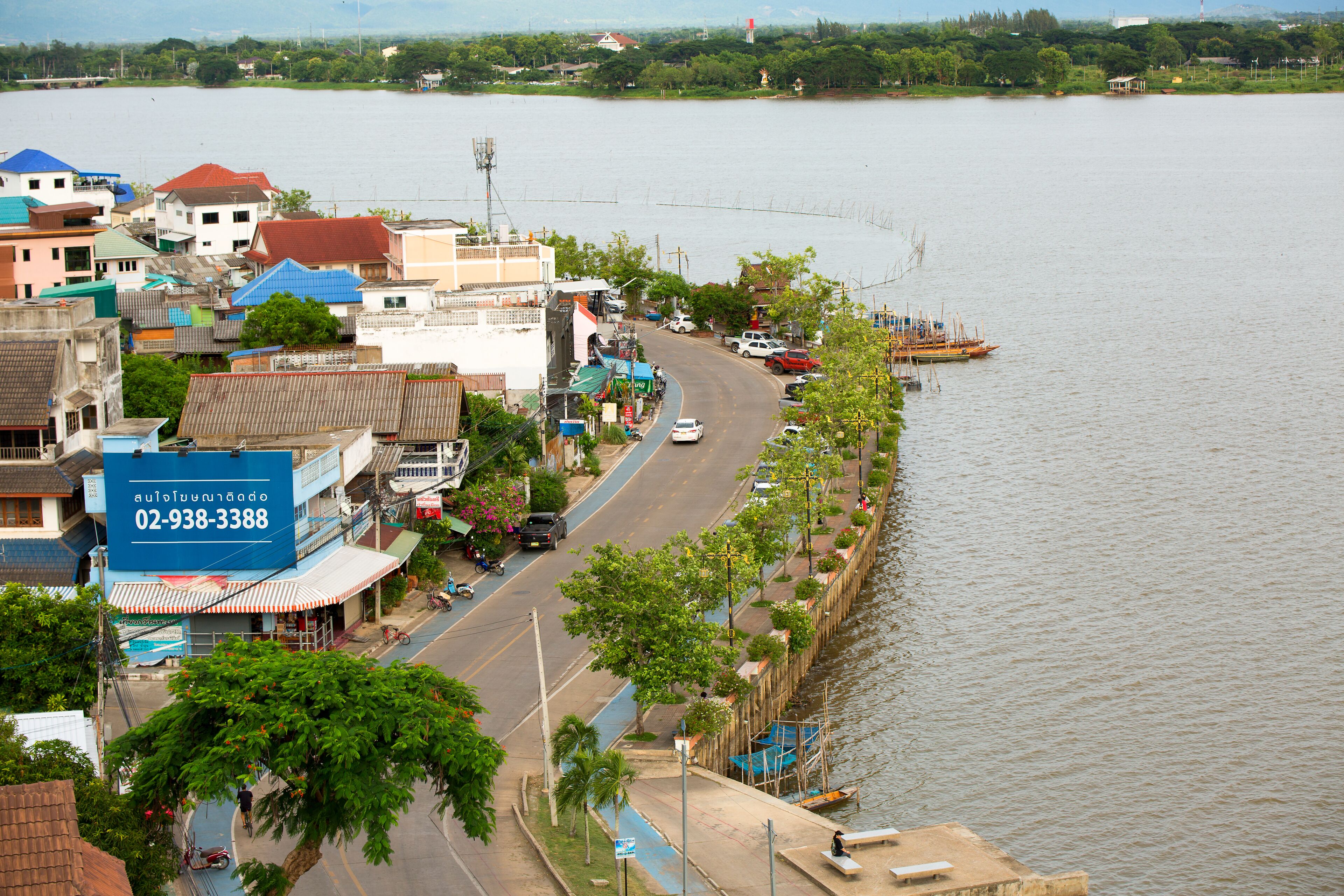 Un pueblo a orillas del río con edificios, una carretera y un muelle para barcos.