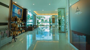 A spacious lobby with a polished floor, a large painting, and a display of woven bags. - Phuglong Hotel (Phayao)