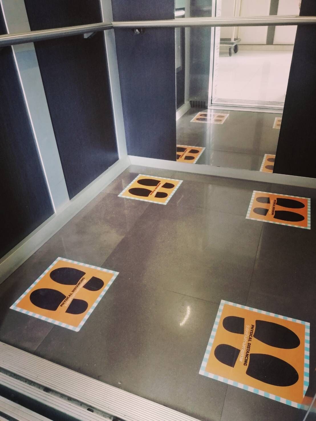 An elevator with floor markings indicating physical distancing.