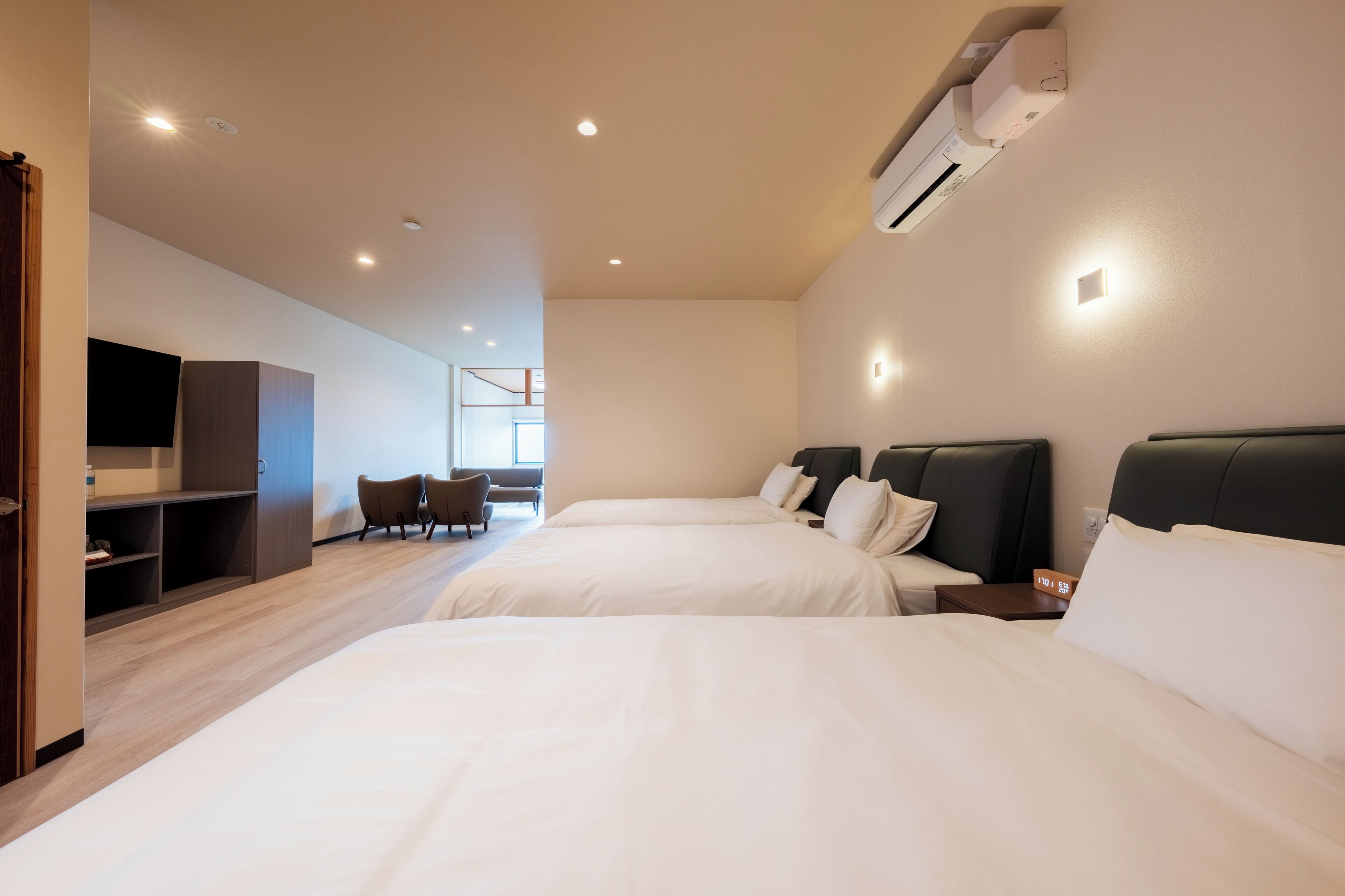Habitación de hotel con dos camas, un escritorio, una silla y un televisor.