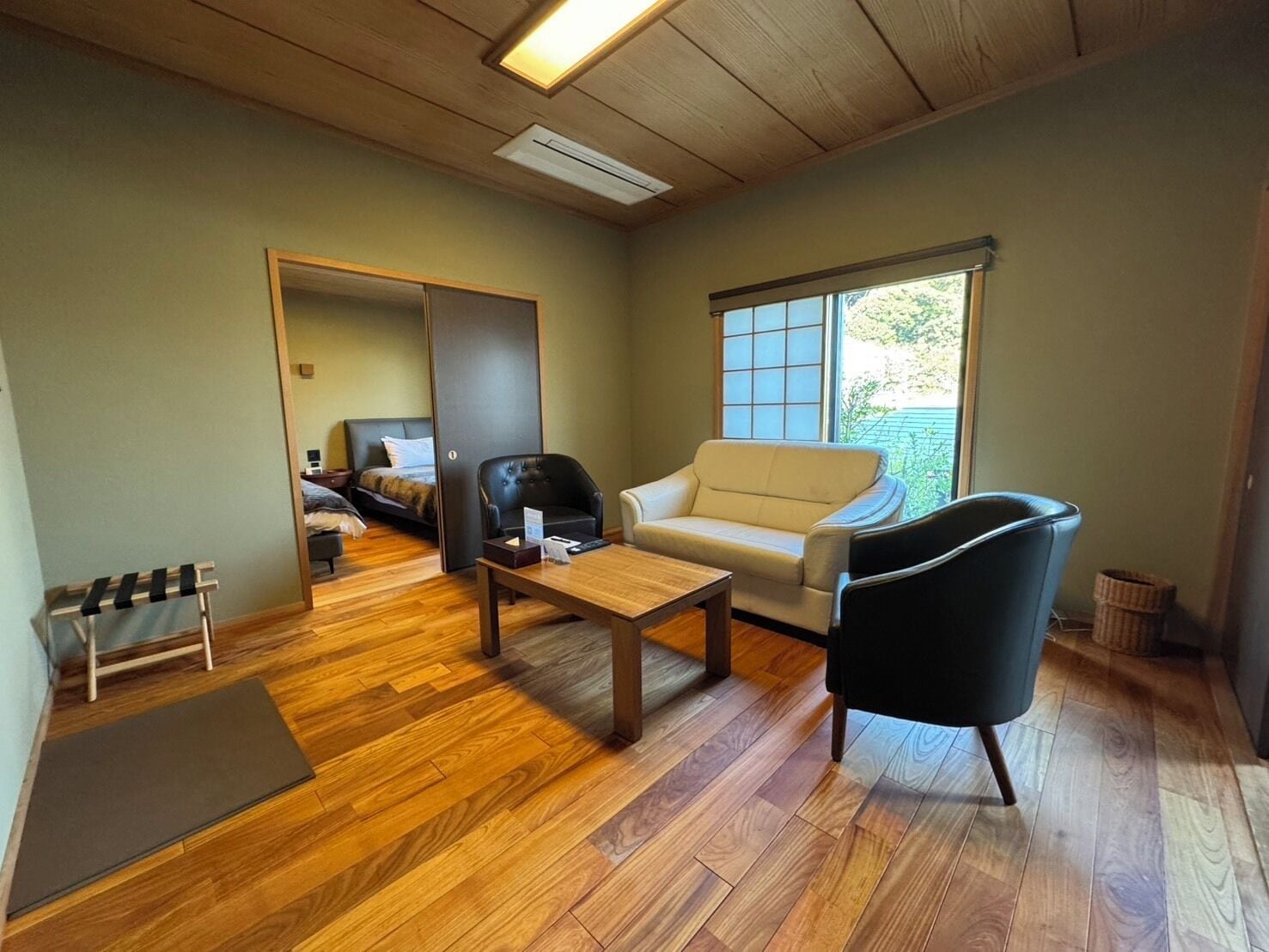 A room with a bed, a sofa, a chair, a table, and a window.
