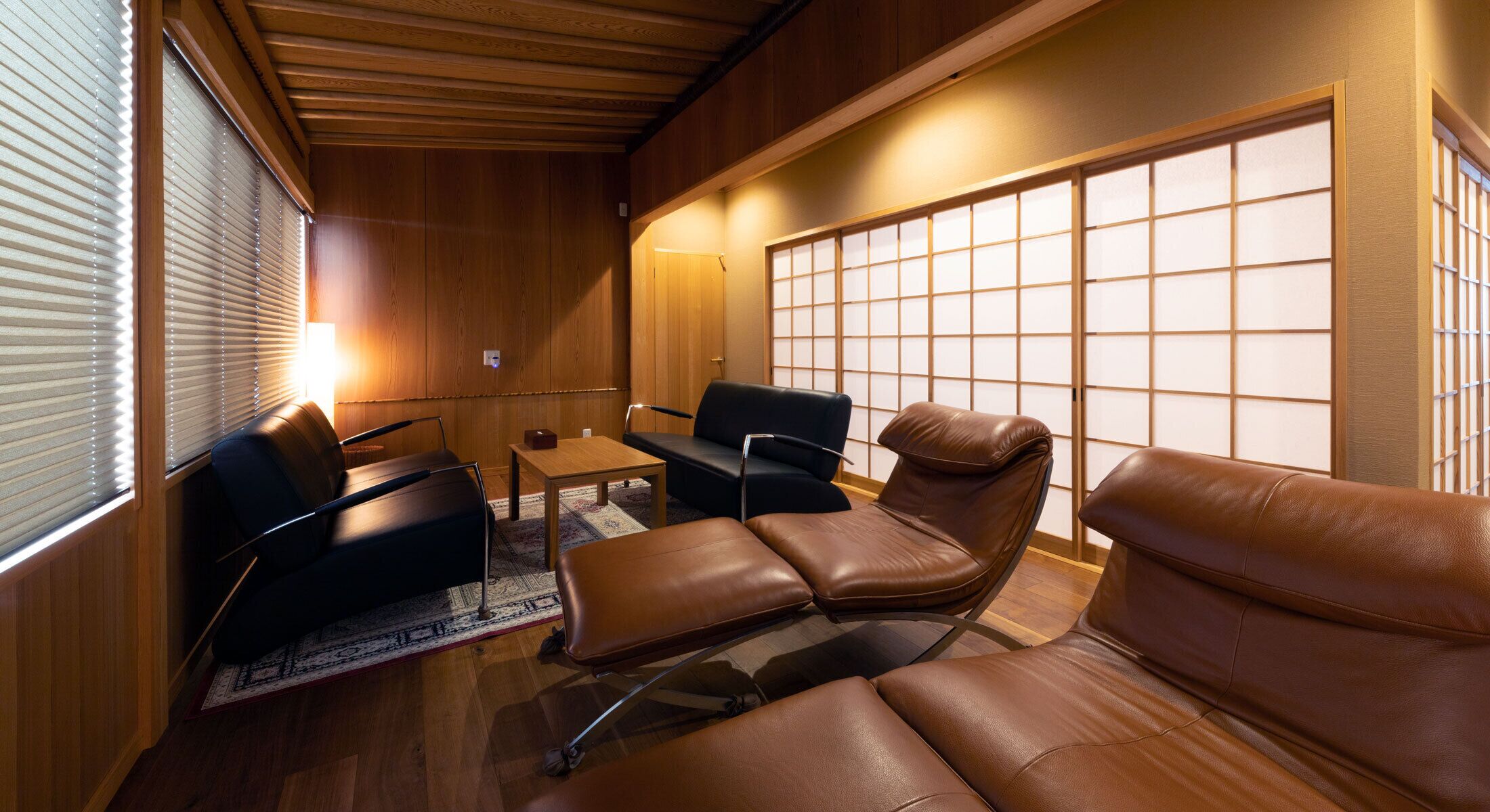 A compact room with wooden paneling, a sofa, a chair, and a small table.