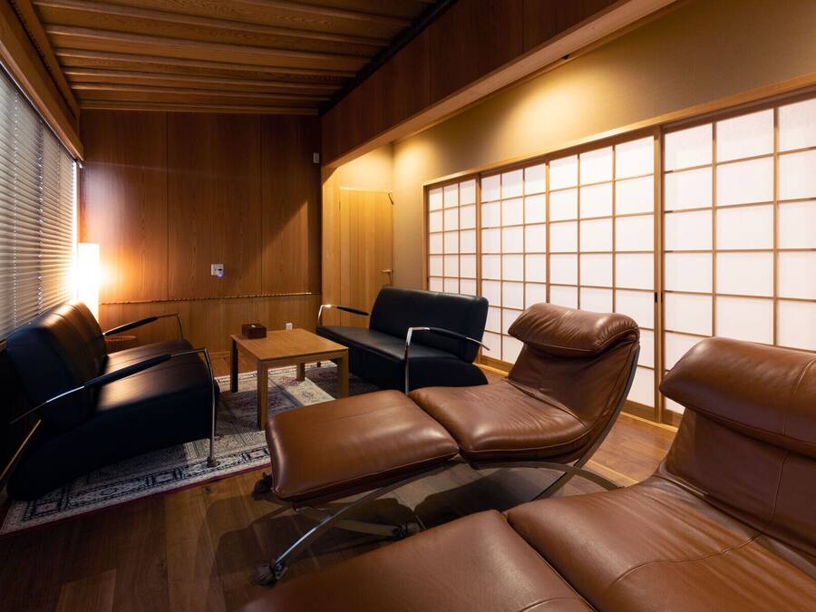 A compact room with wooden paneling, a sofa, a chair, and a small table.