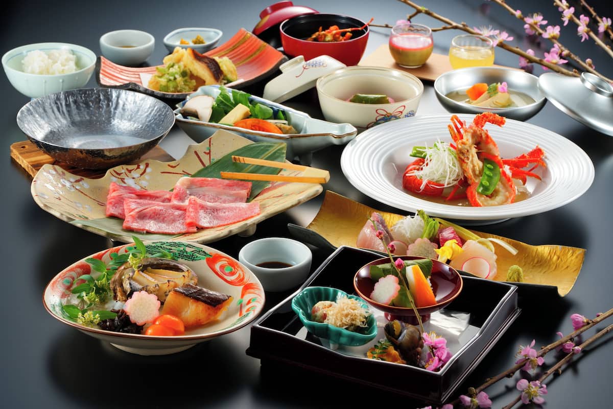 A variety of Japanese dishes arranged on a table, including sushi, sashimi, and other traditional foods.