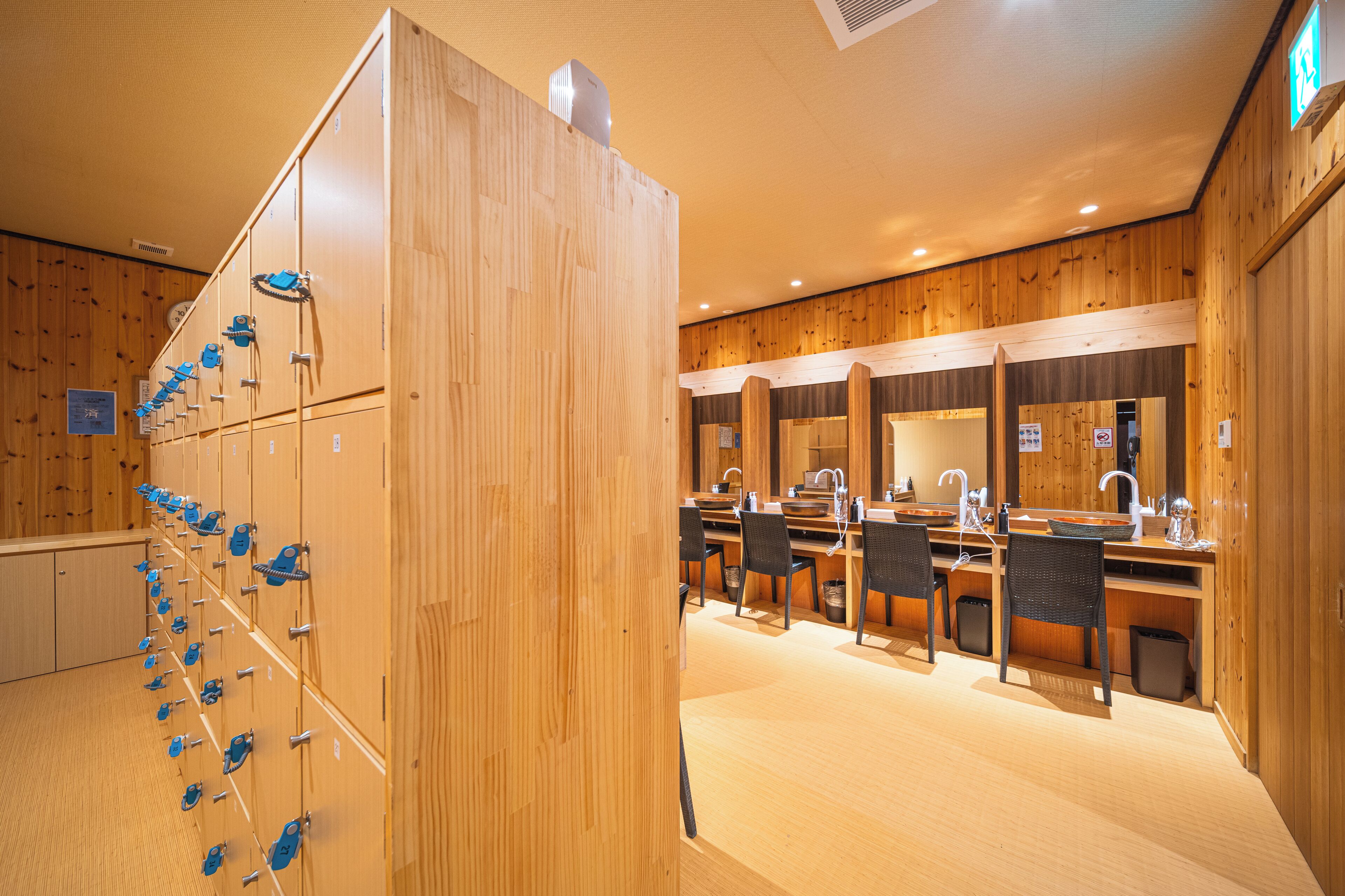 Interior de madera con taquillas, zona de lavamanos y espejo.