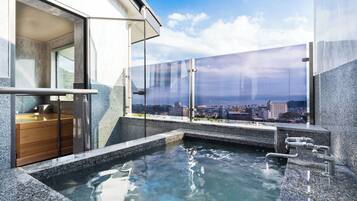 A modern spa area with a hot tub, wooden bath, and a city view through large glass windows.