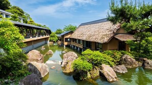 Un ryokan japonés tradicional con tejados de paja, un estanque de carpas koi y un jardín tranquilo.