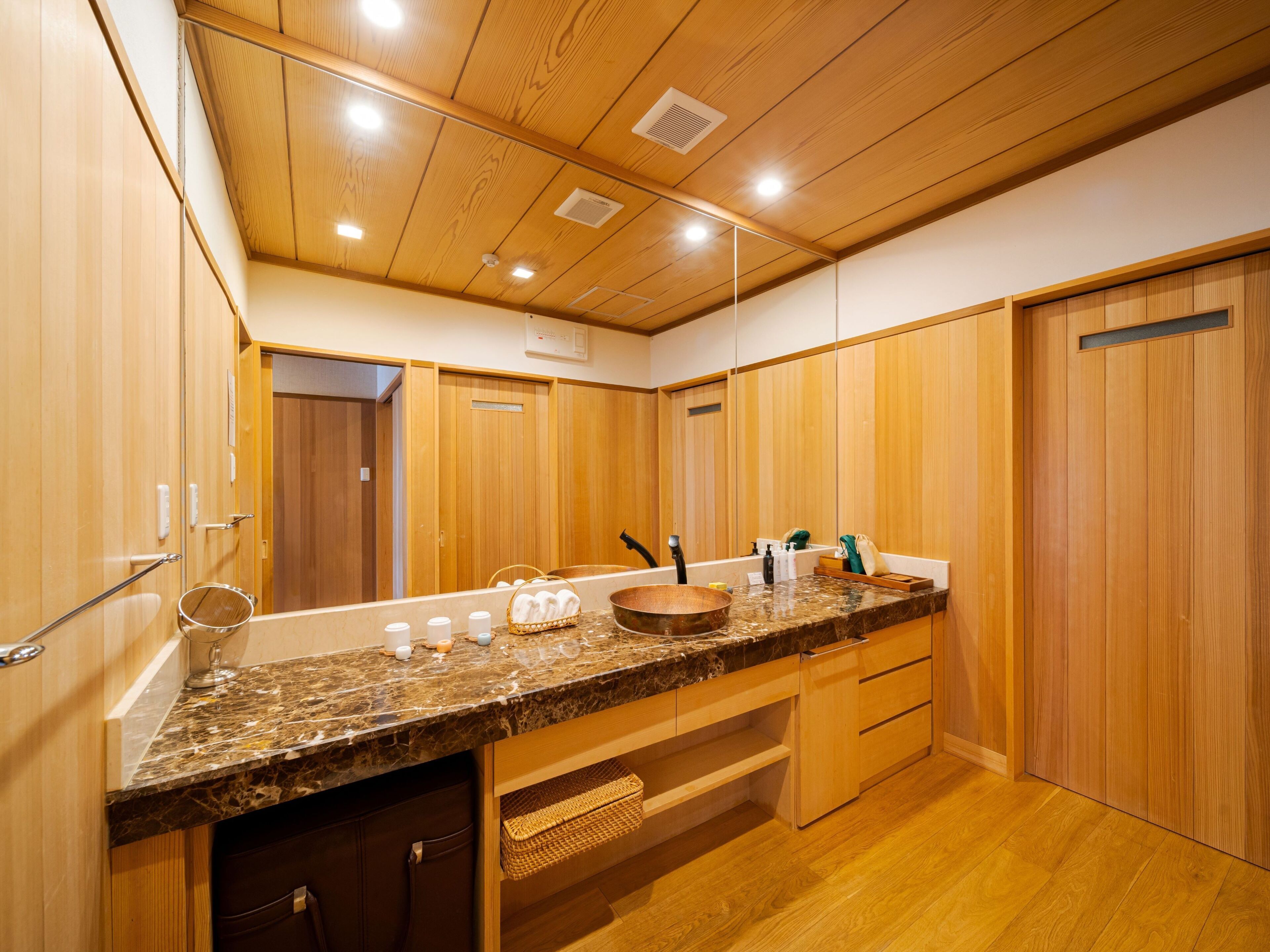 A modern bathroom with wooden paneling, a granite countertop, and a large mirror.
