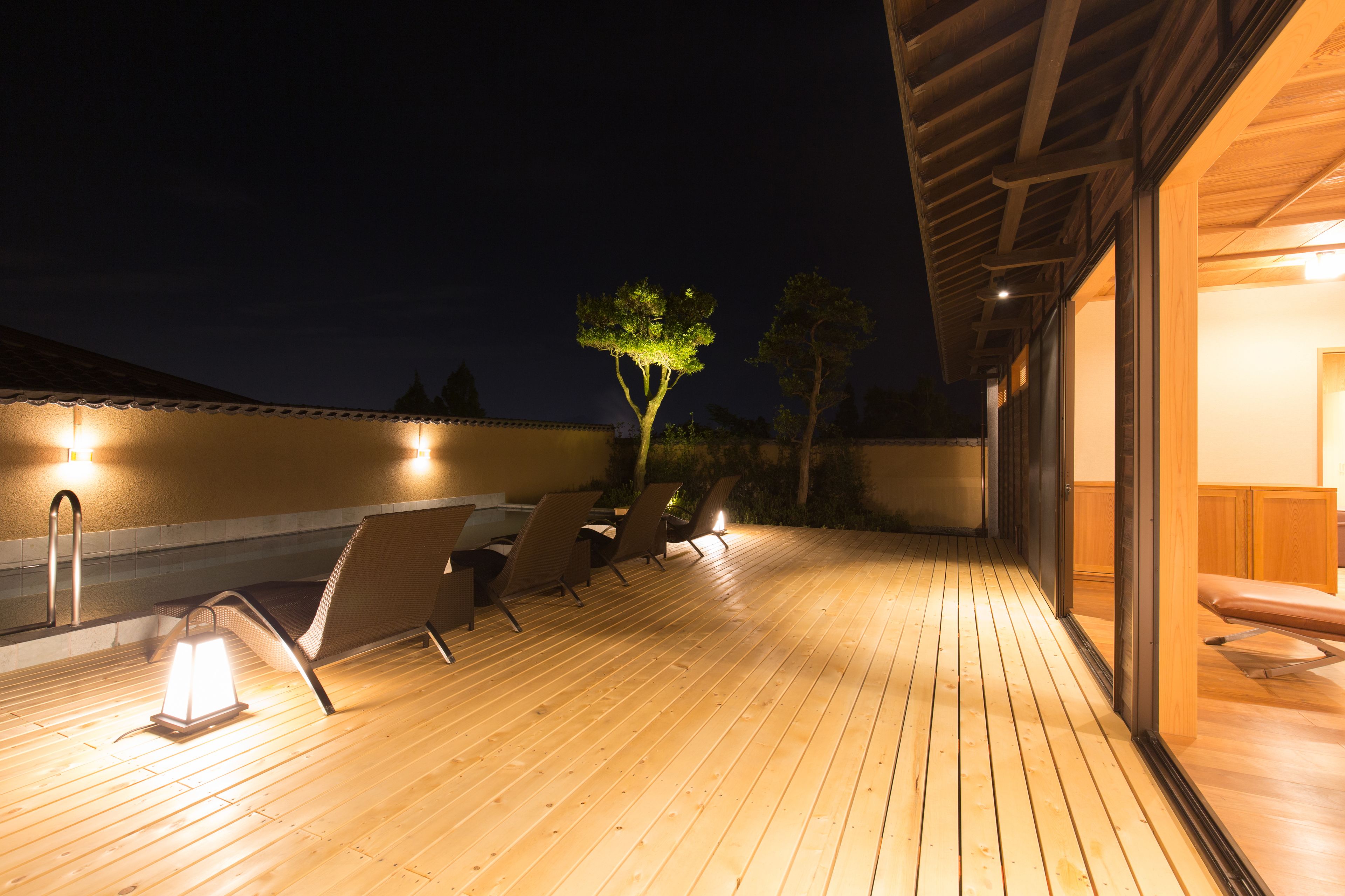 A wooden deck with outdoor seating and a tree.