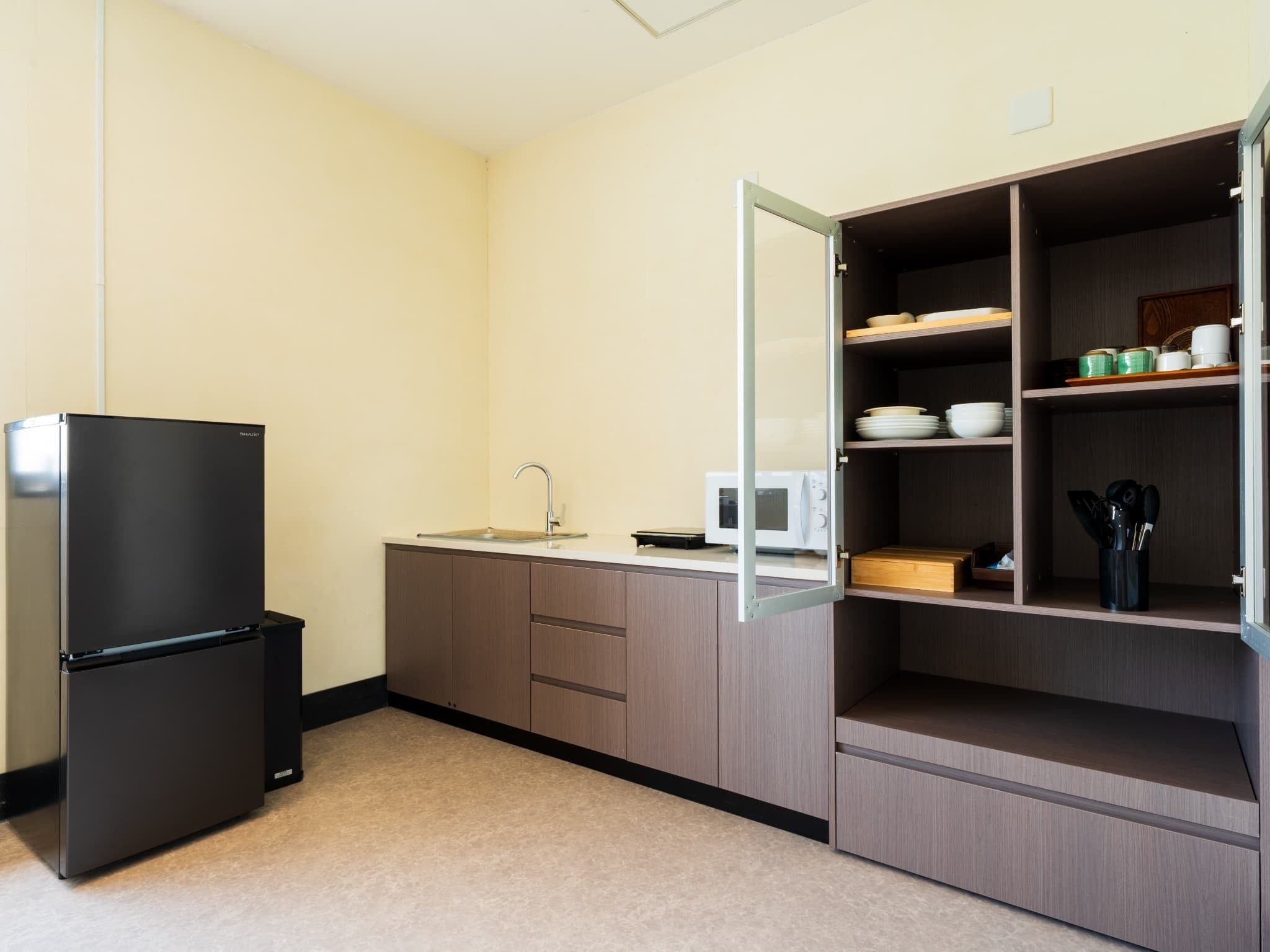 A compact kitchen with a built-in refrigerator, a microwave, and a sink.