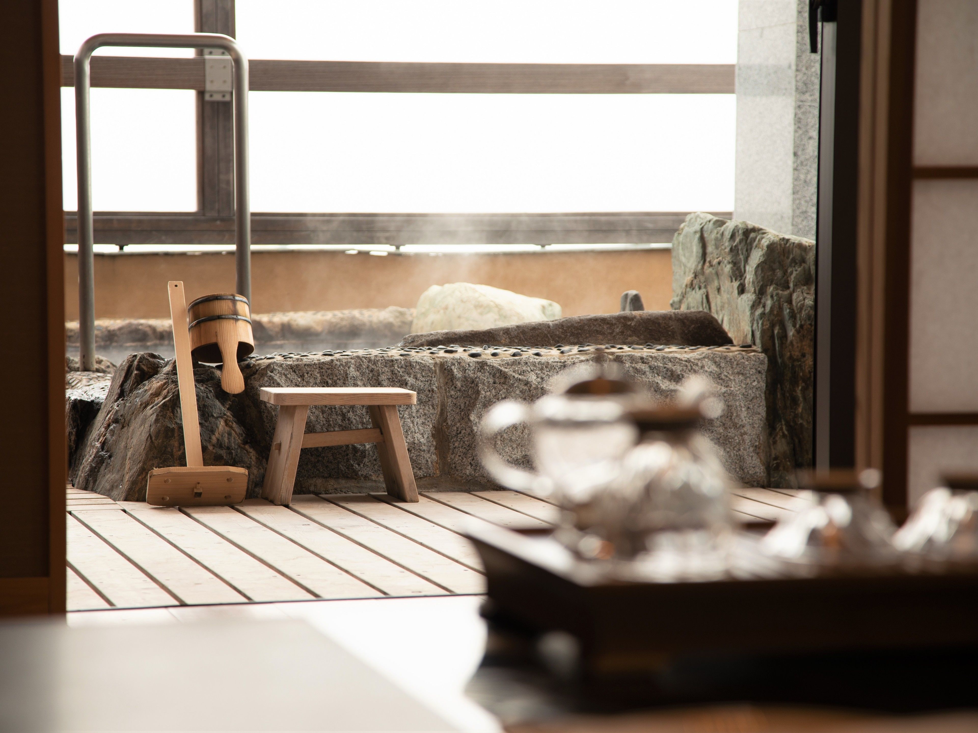 Une pièce de style japonais traditionnel, avec un sol recouvert de tatamis, un petit tabouret en bois, un tonneau de saké et une cheminée en pierre.