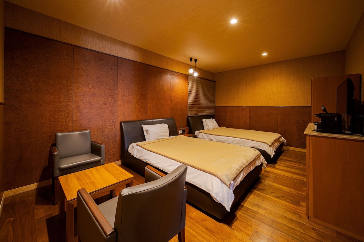 A hotel room with two beds, a desk, and a chair.