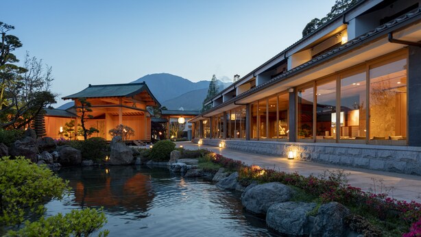 Un edificio tradicional al estilo japonés con un estanque de peces koi y jardín de rocas.