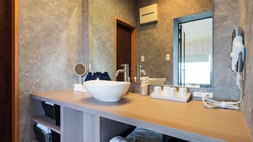 A modern bathroom with a large sink, mirror, and a hairdryer mounted on the wall.