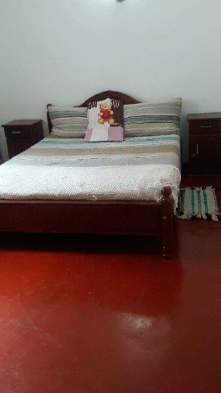 A bed with a wooden frame, a white mattress, and striped pillows. There are two bedside tables with lamps.