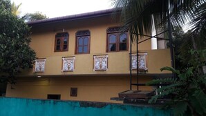 A two-story building with a yellow facade, decorative window frames, and a balcony with a railing. - Srilusa Home Stay Hikkaduwa (Hikkaduwa)