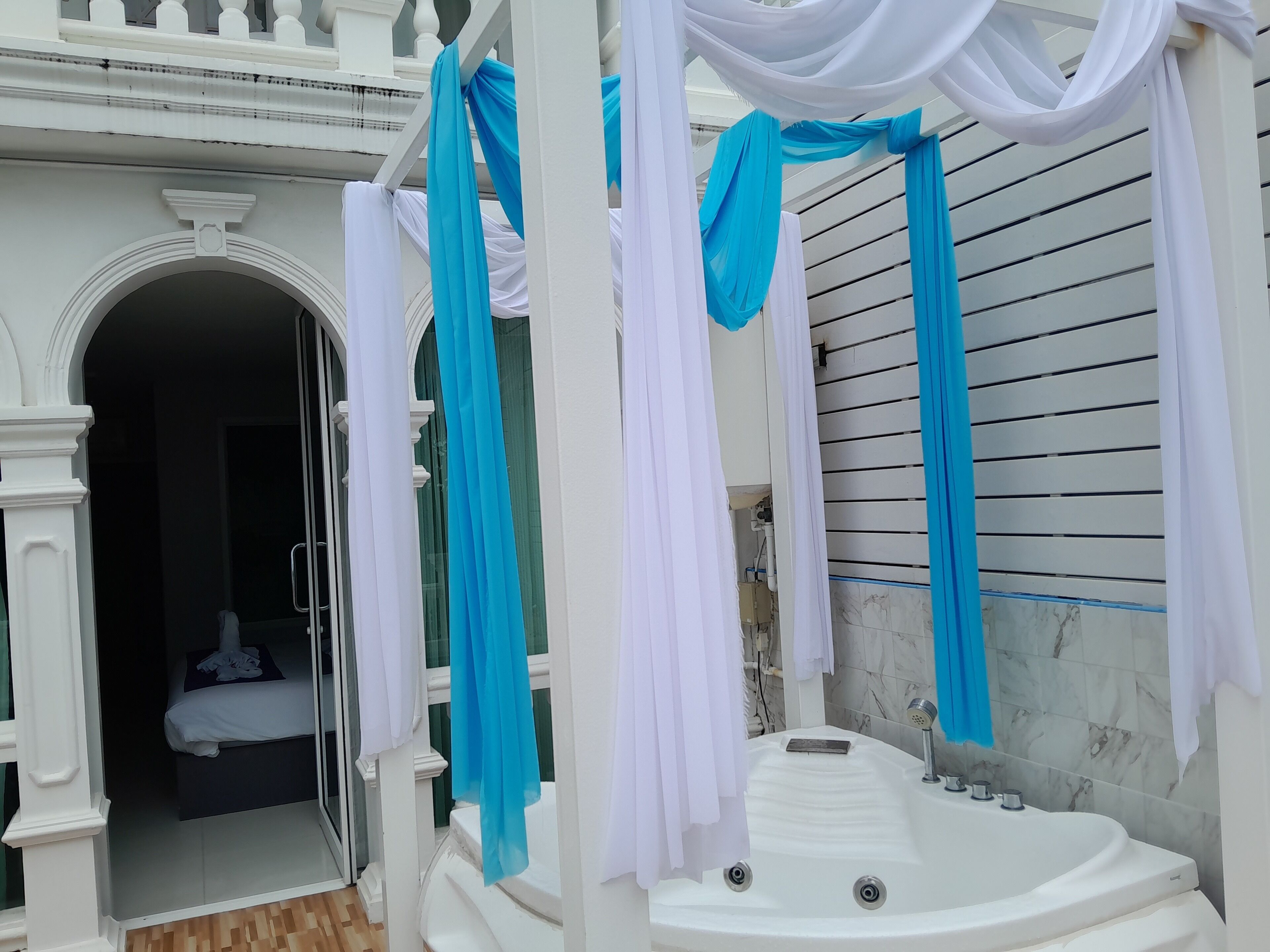 Un área de spa con una bañera de hidromasaje, columnas blancas y cortinas azules.