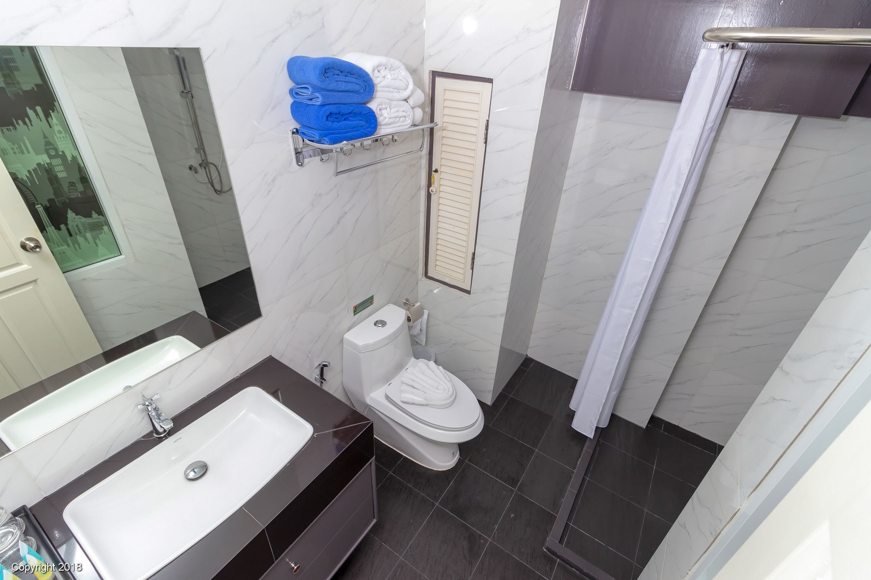 Un baño con lavamanos blanco, inodoro y zona de ducha.