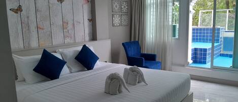 Camera d'albergo con un letto grande, una poltrona blu e vista sulla piscina.