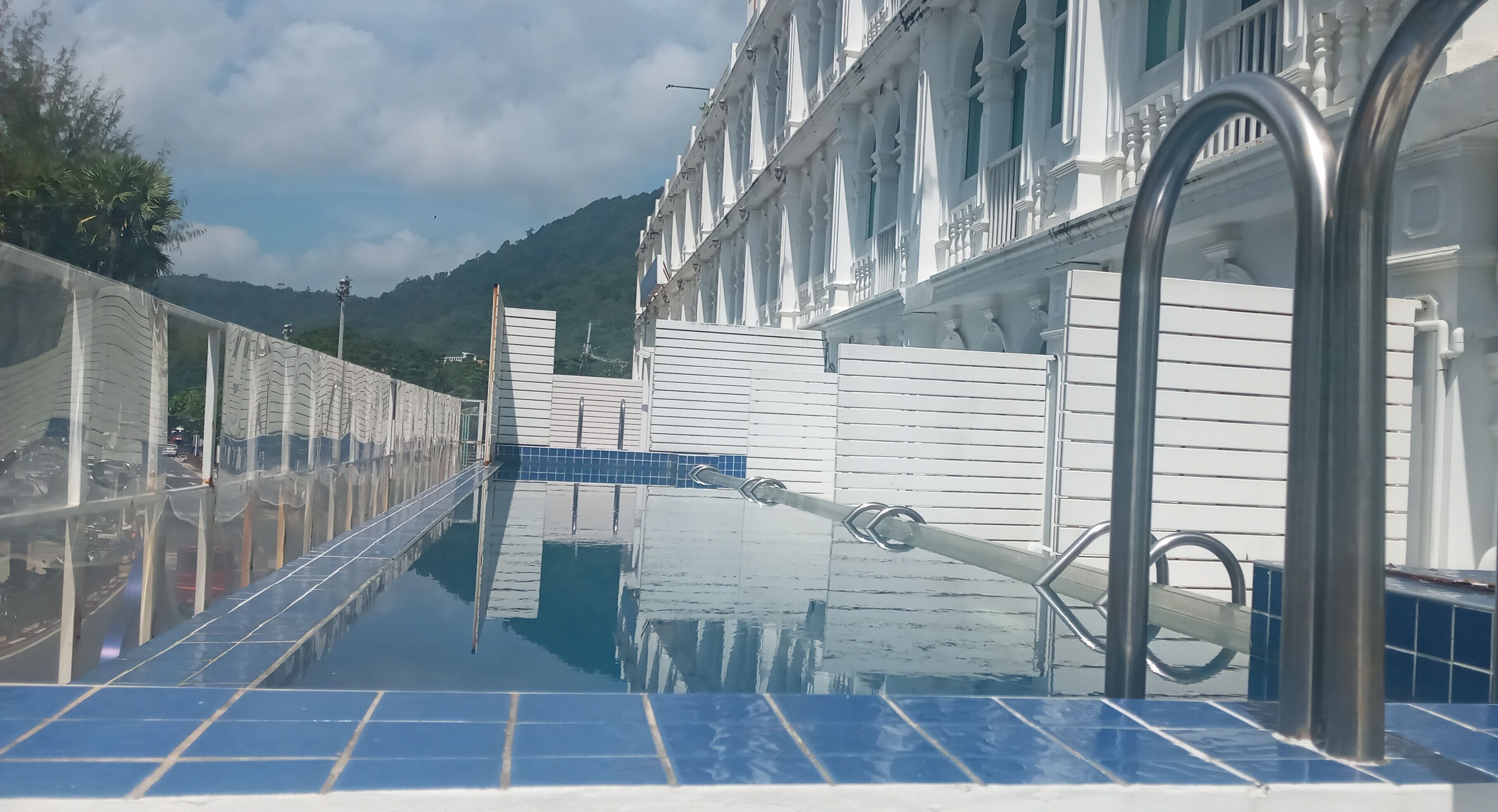 A poolside area with a clear view of a building with white walls and blue-tiled steps.