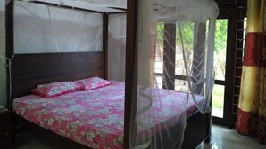 A four-poster bed with a canopy, a wooden headboard, and a floral bedspread. - Nishan Surf Inn (Matara)