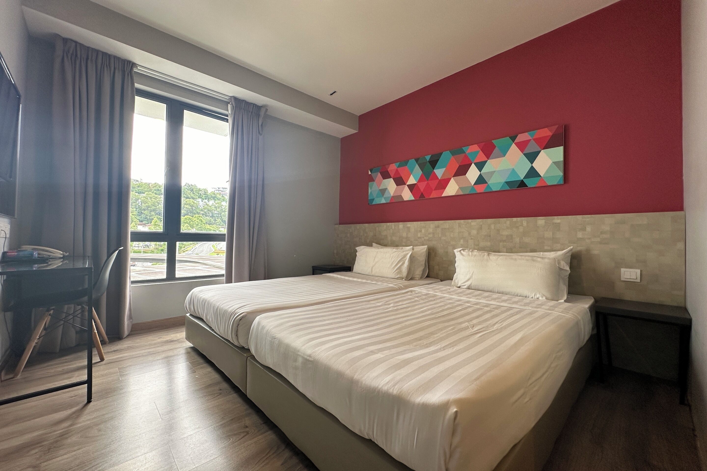 Una habitación de hotel con una cama grande, un escritorio y una ventana con cortinas.