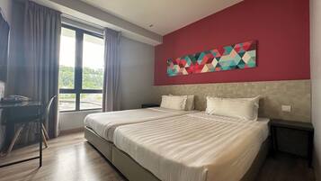 Una habitación de hotel con una cama grande, un escritorio y una ventana con cortinas.