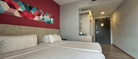 A hotel room with a large bed, a red accent wall, a geometric art piece, a mirror, and a door leading to another room.