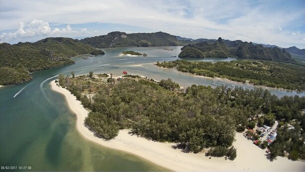Vista aérea de uma área costeira com uma baía, praias de areia e florestas densas.