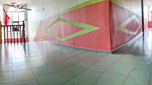 Um corredor com piso ladrilhado, escada e parede vermelha com padrões geométricos.
