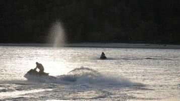 Una persona en un jet ski levantando una lluvia de agua.