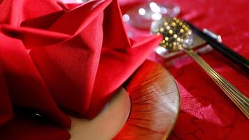A close-up of a red fabric, possibly a napkin, with a gold-colored plate and a pair of chopsticks on a red tablecloth.