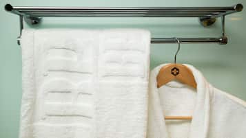 A white towel hanging on a metal towel rack in a bathroom with a light green wall.