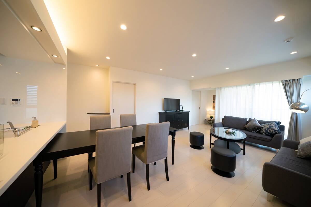 A modern living room with a dining area, a sofa, and a TV.