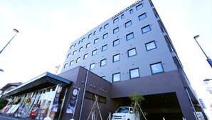 Un hôtel moderne, avec un bâtiment à la façade plate, de nombreuses fenêtres et un espace d’entrée abrité.