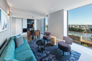 Una sala de estar moderna con un sofá, sillas, una mesa de centro y vistas a un río y un paisaje urbano.