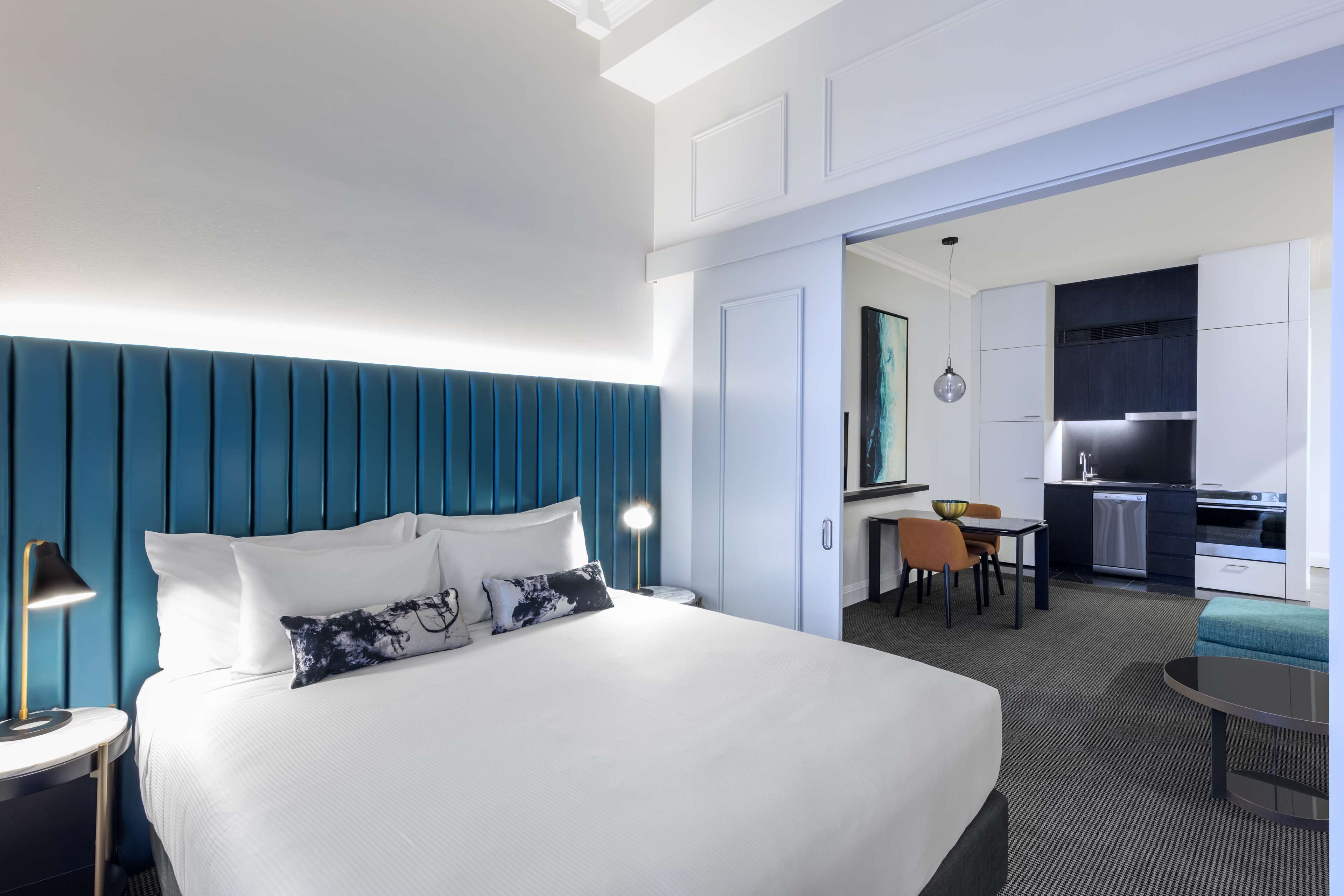 Una habitación de hotel con una cama grande, un escritorio, una silla y una kitchenette.