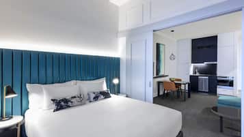 Una habitación de hotel con una cama grande, un escritorio, una silla y una kitchenette.