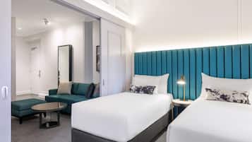 Ein modernes Hotelzimmer mit zwei Betten, einem Sofa, einem kleinen Tisch und einem Spiegel.