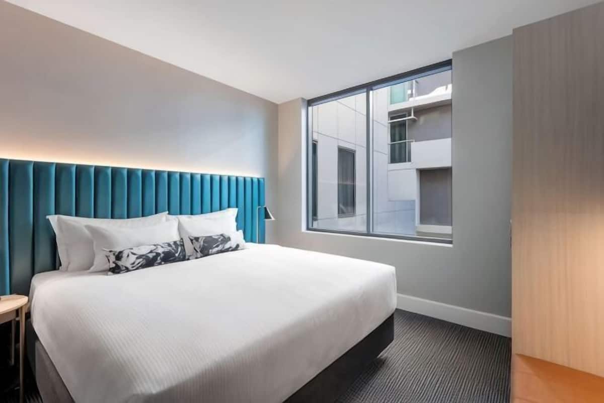 A hotel room with a bed, a window, a wardrobe, and a nightstand.