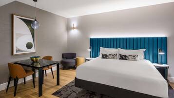 Quarto de hotel moderno com uma cama grande, uma mesa de jantar e um espaço de estar.