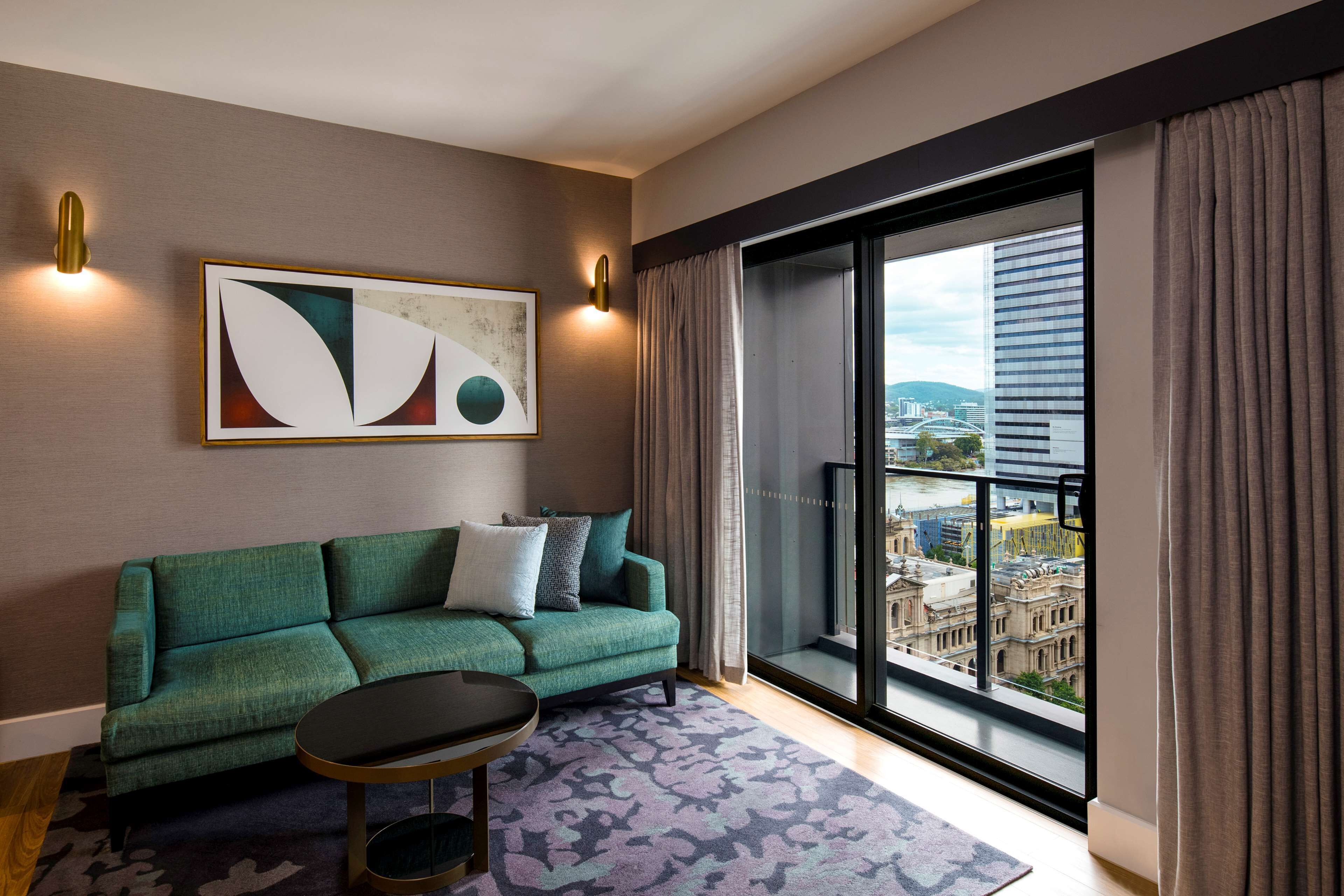 Ein modernes Wohnzimmer mit einem grünen Sofa, einem Couchtisch und einem großen Fenster mit Blick auf die Stadt.
