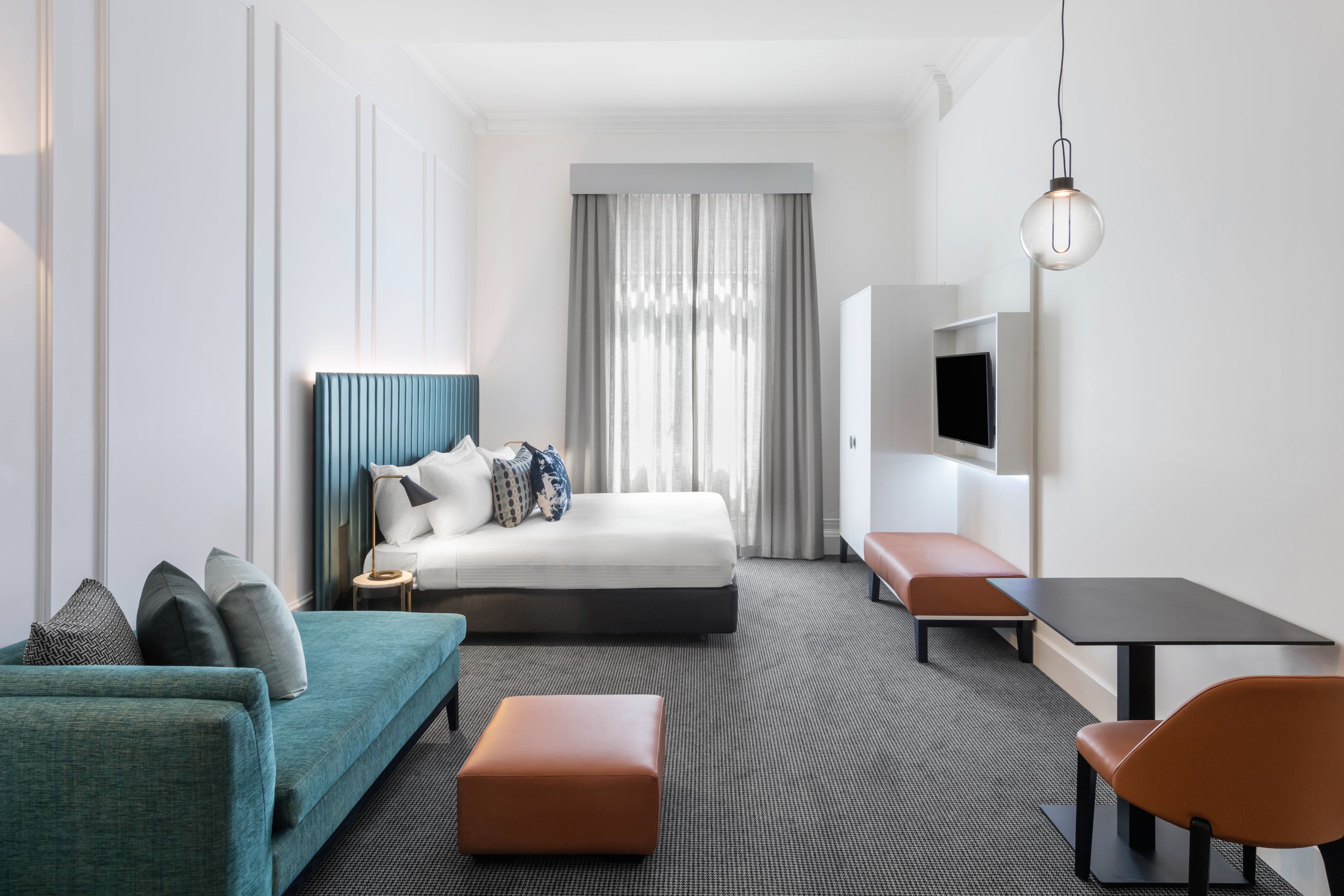 Una habitación de hotel moderna con cama, sofá, mesa y televisor.